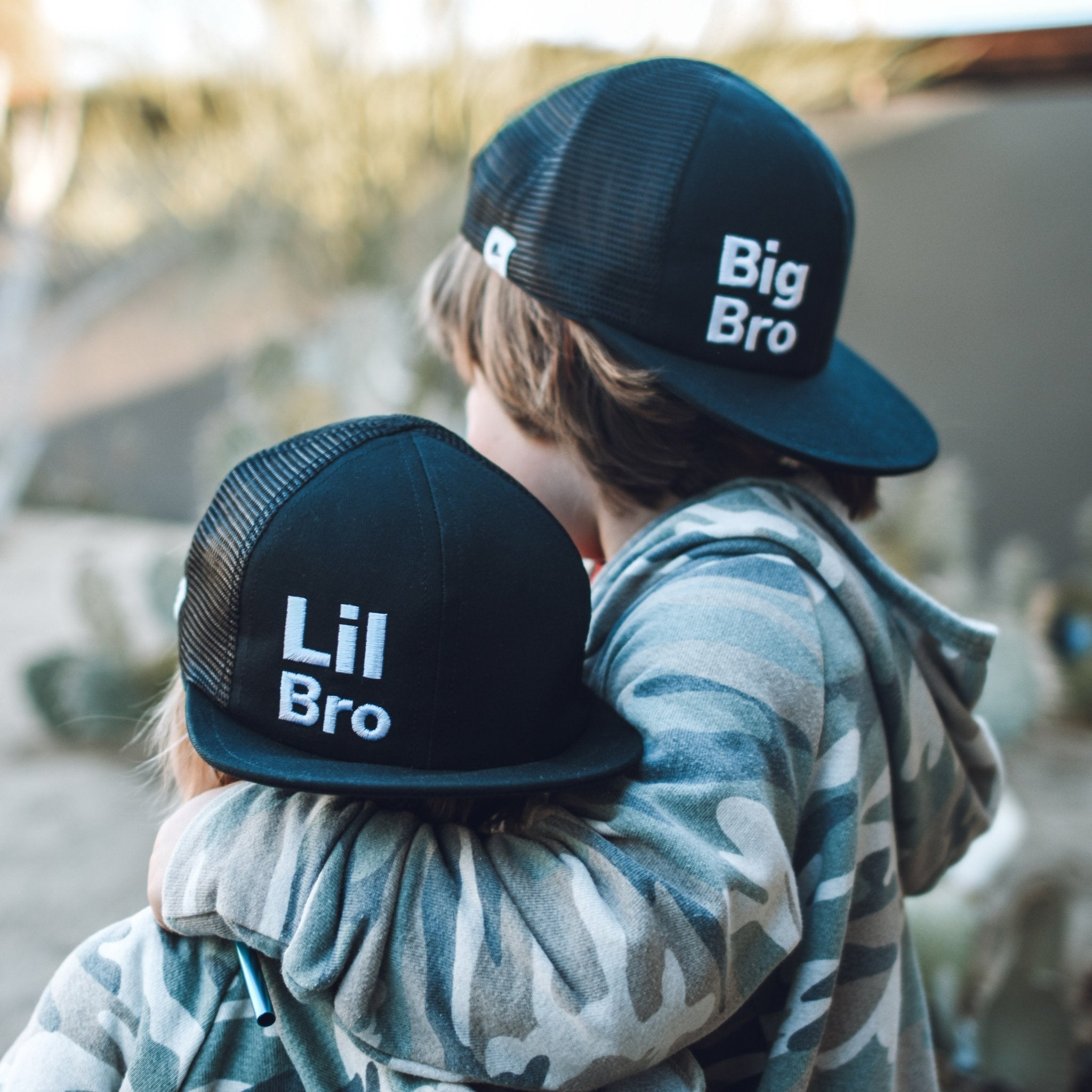 Image of two boys one wearing lil bro trucker hat and the other wearing big bro trucker hat