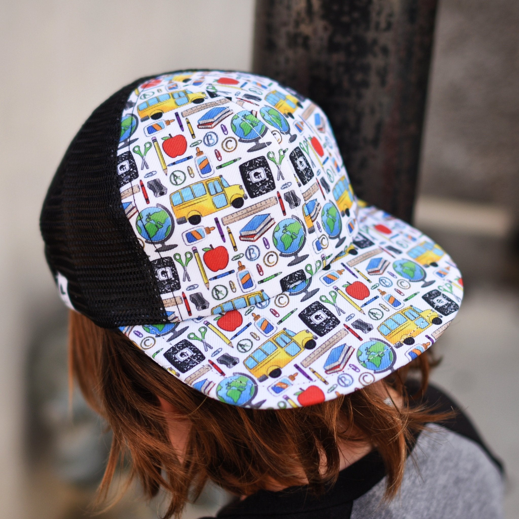 image of the back of the Back to School Trucker - George Hats, a boys trucker hat with school-themed print of school buses, globe, apple, and more! 