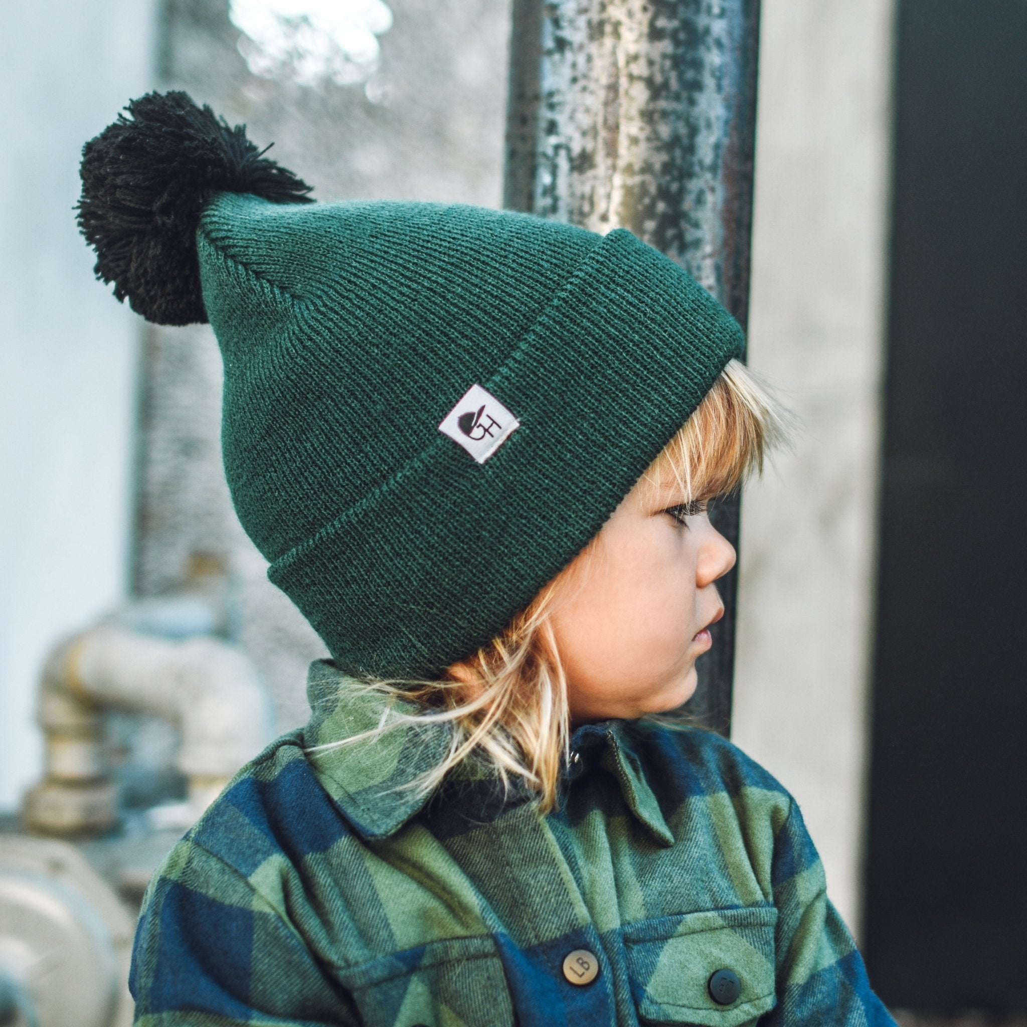 Kid in a green flannel shirt wearing the Hunter Pom Beanie from George Hats.