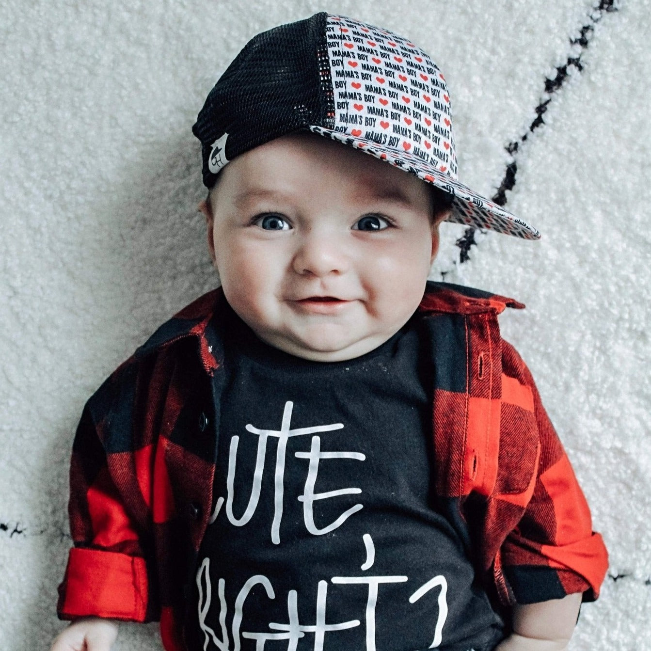 Image of a toddler wearing a kids trucker hat  from George Hats laying on a blanket