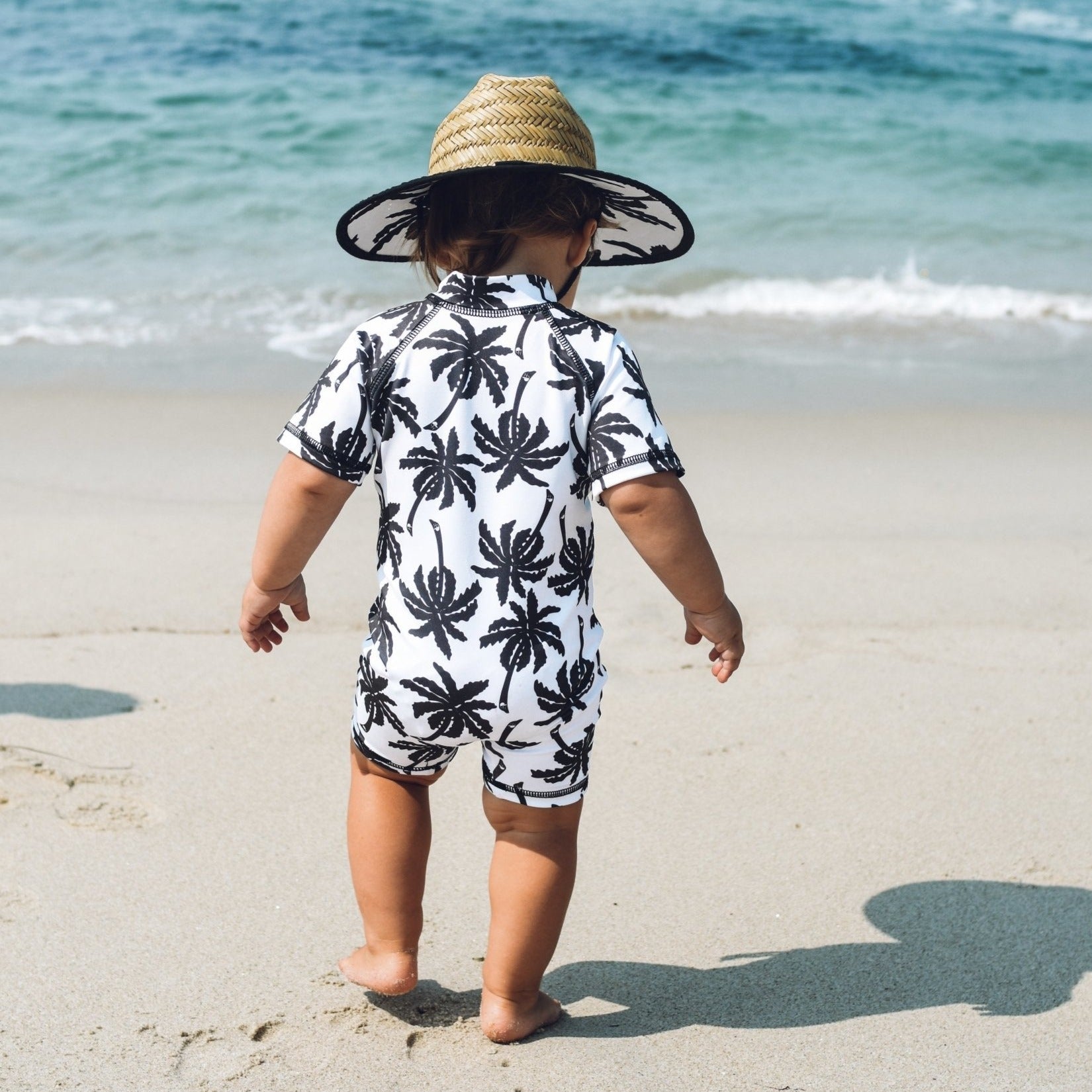 An image of a child in the George Hats Palm Straw Hat and Sunsuit.