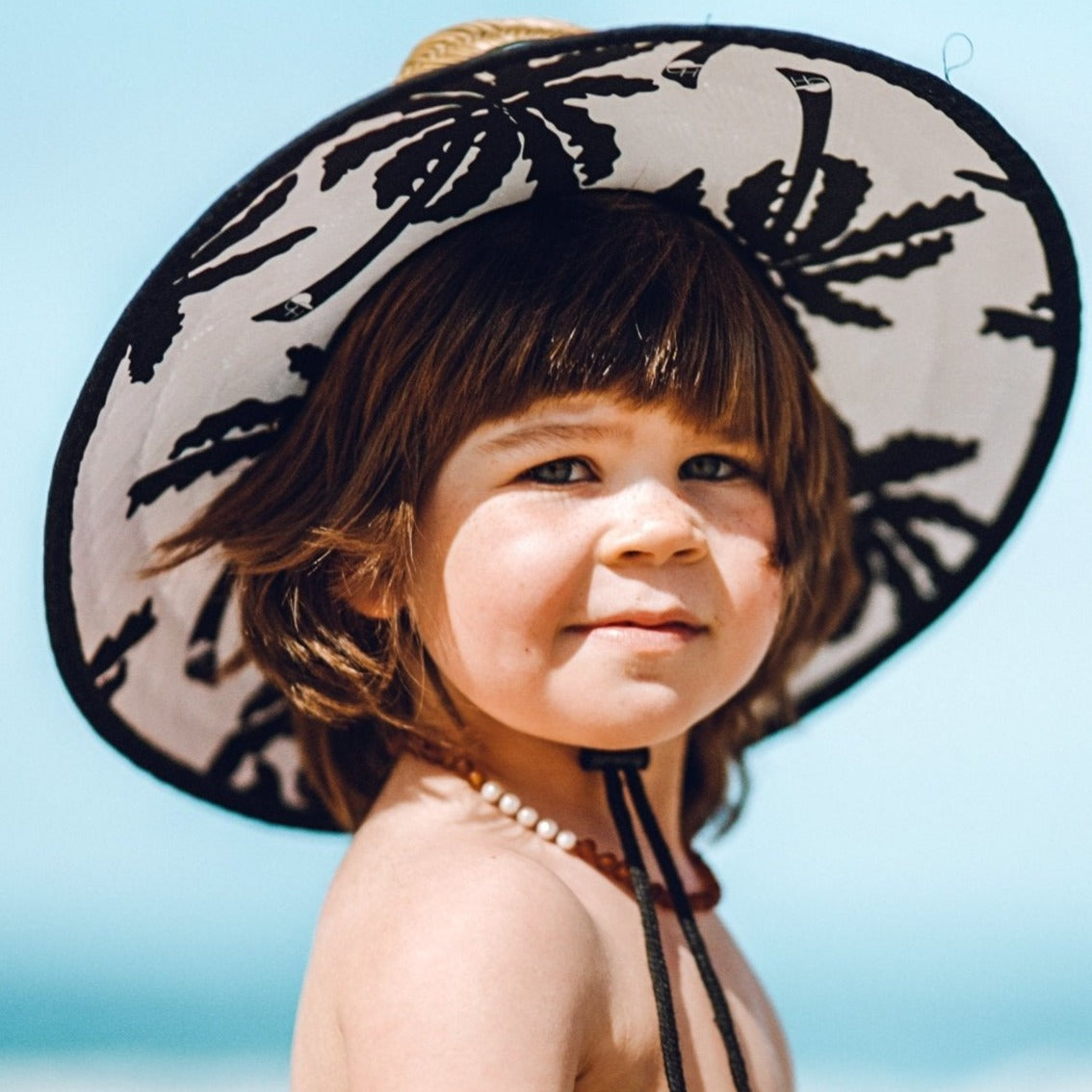 An image of a child in the George Hats Palm Straw Hat.