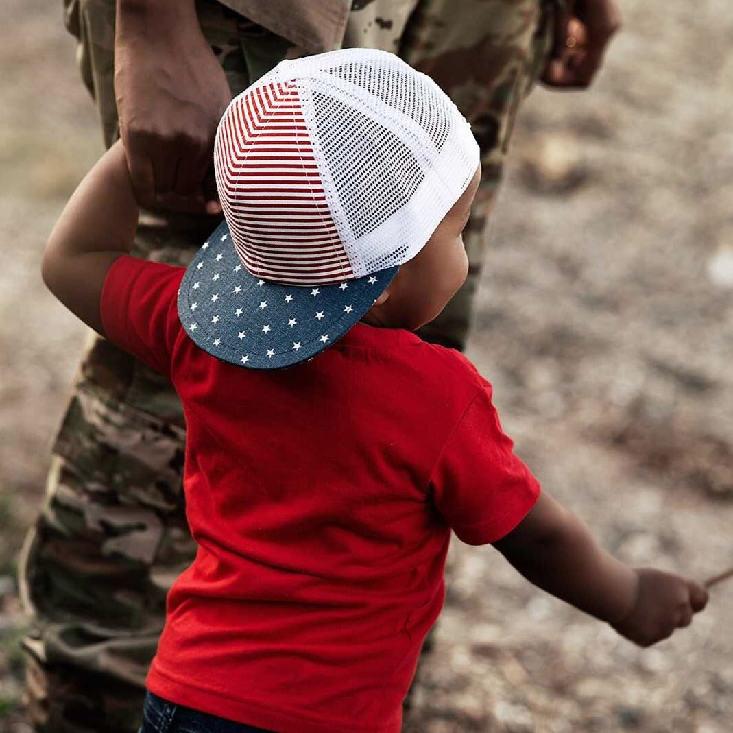 An image of a child holding a flag and wearing a trucker hat.