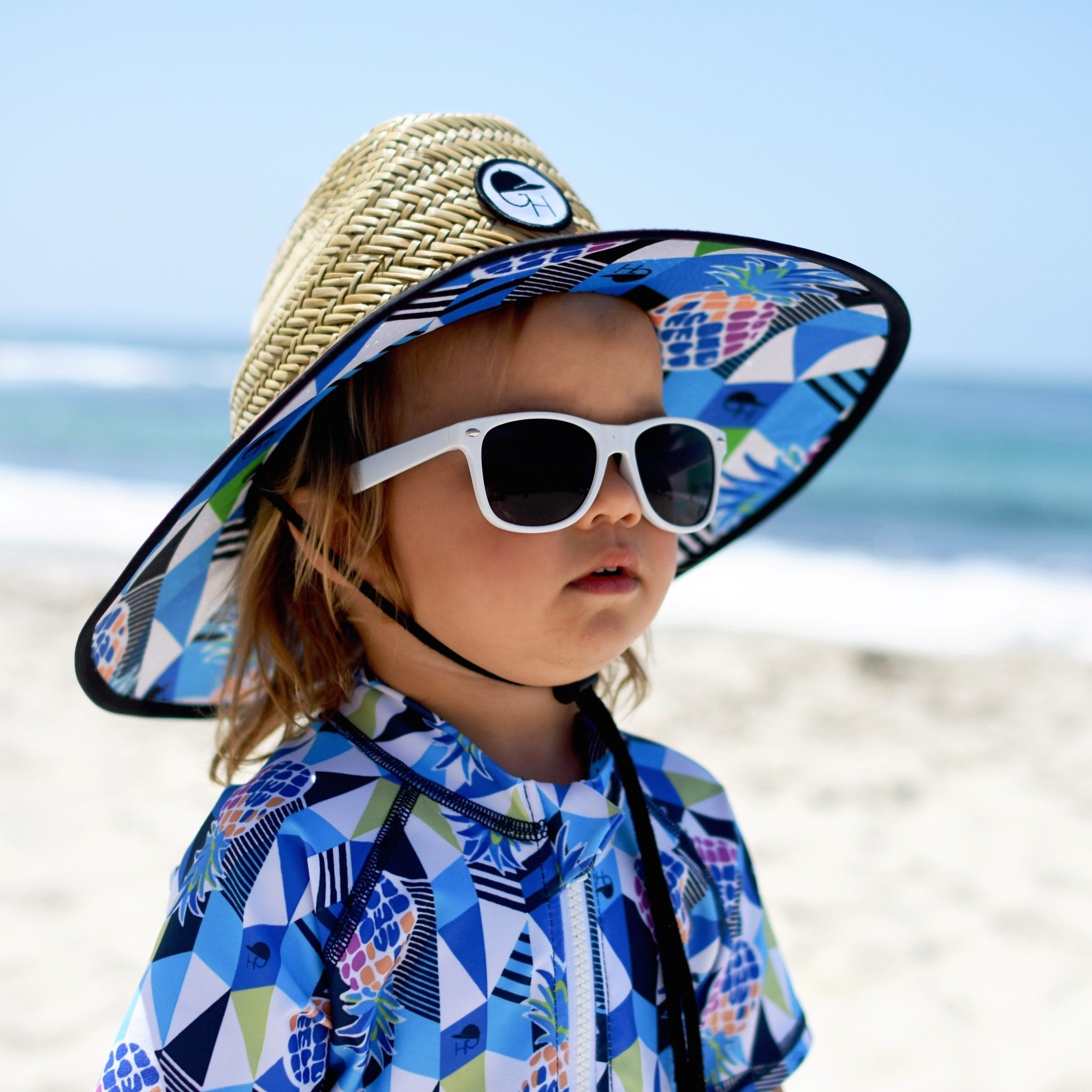 An image of a child wearing the pineapple straw hat from George Hats.
