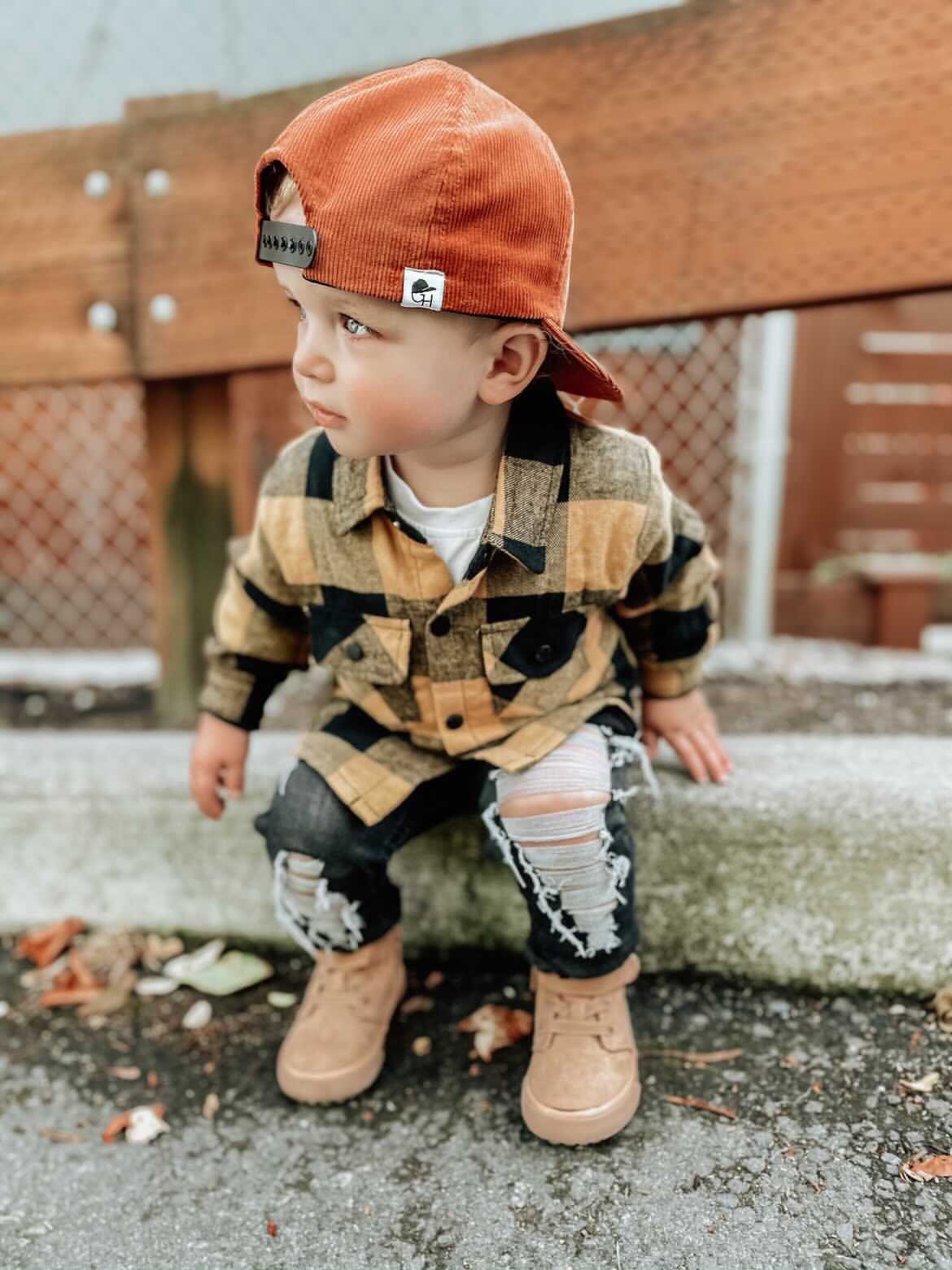 image of a toddler in a flannel shirt wearing the Pumpkin Corduroy Trucker - George Hats boys trucker hat