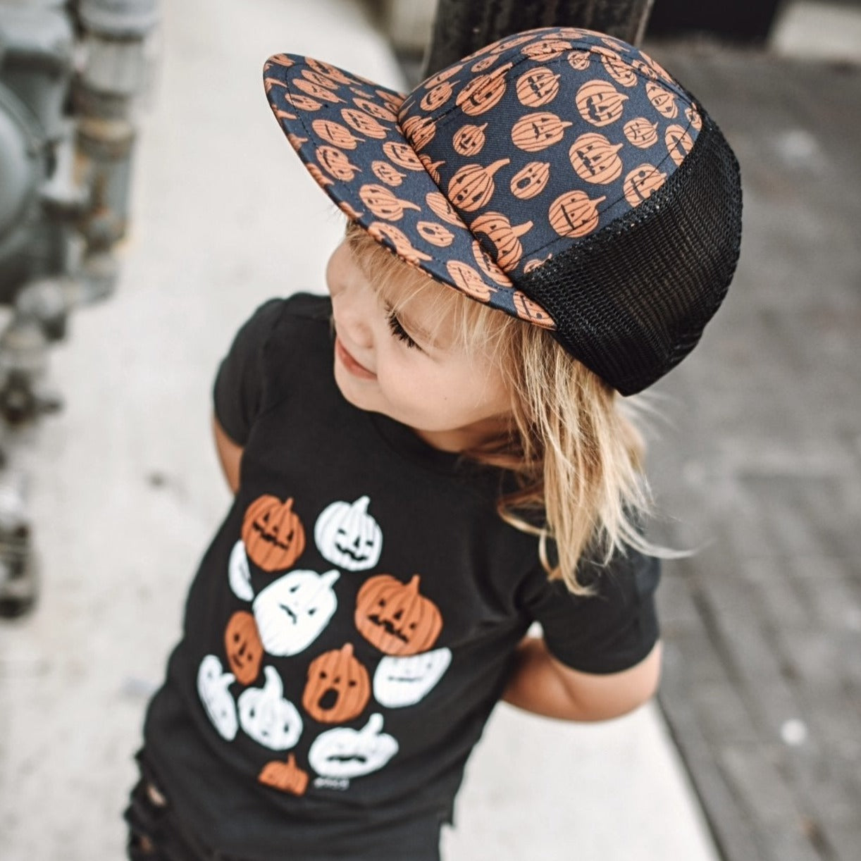 image of a toddler looking upward wearing the Pumpkin Trucker Rags Collab - George Hats baby snapback hat
