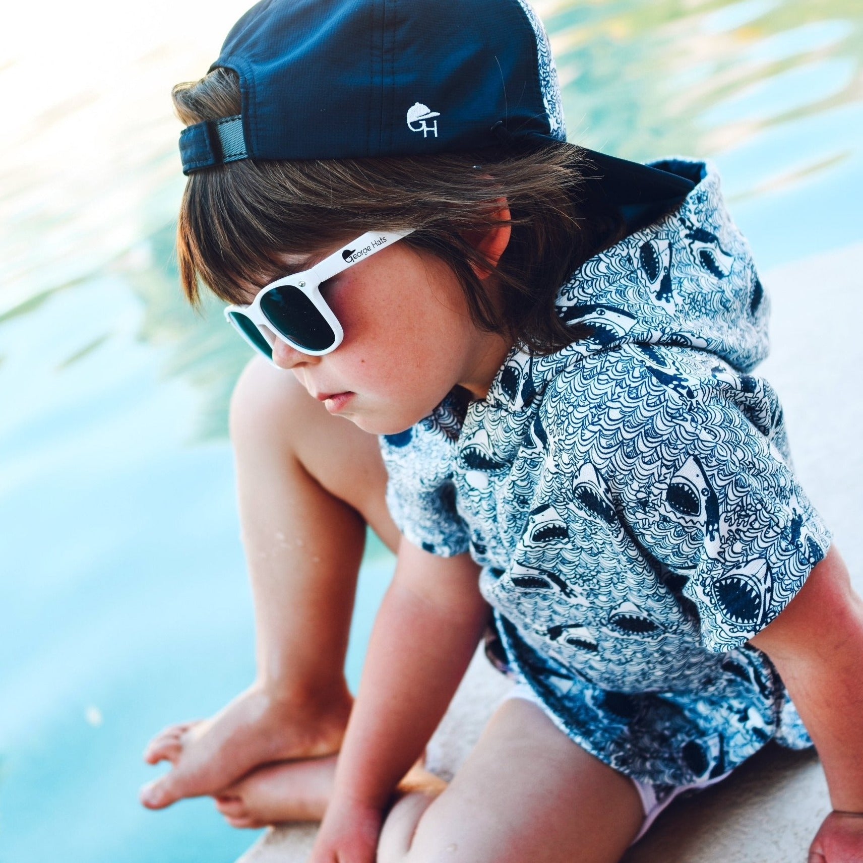 Image of a boy at a pool wearing a snapback hat and sun protective hoodie -Shark Beach Hoodie - George Hats