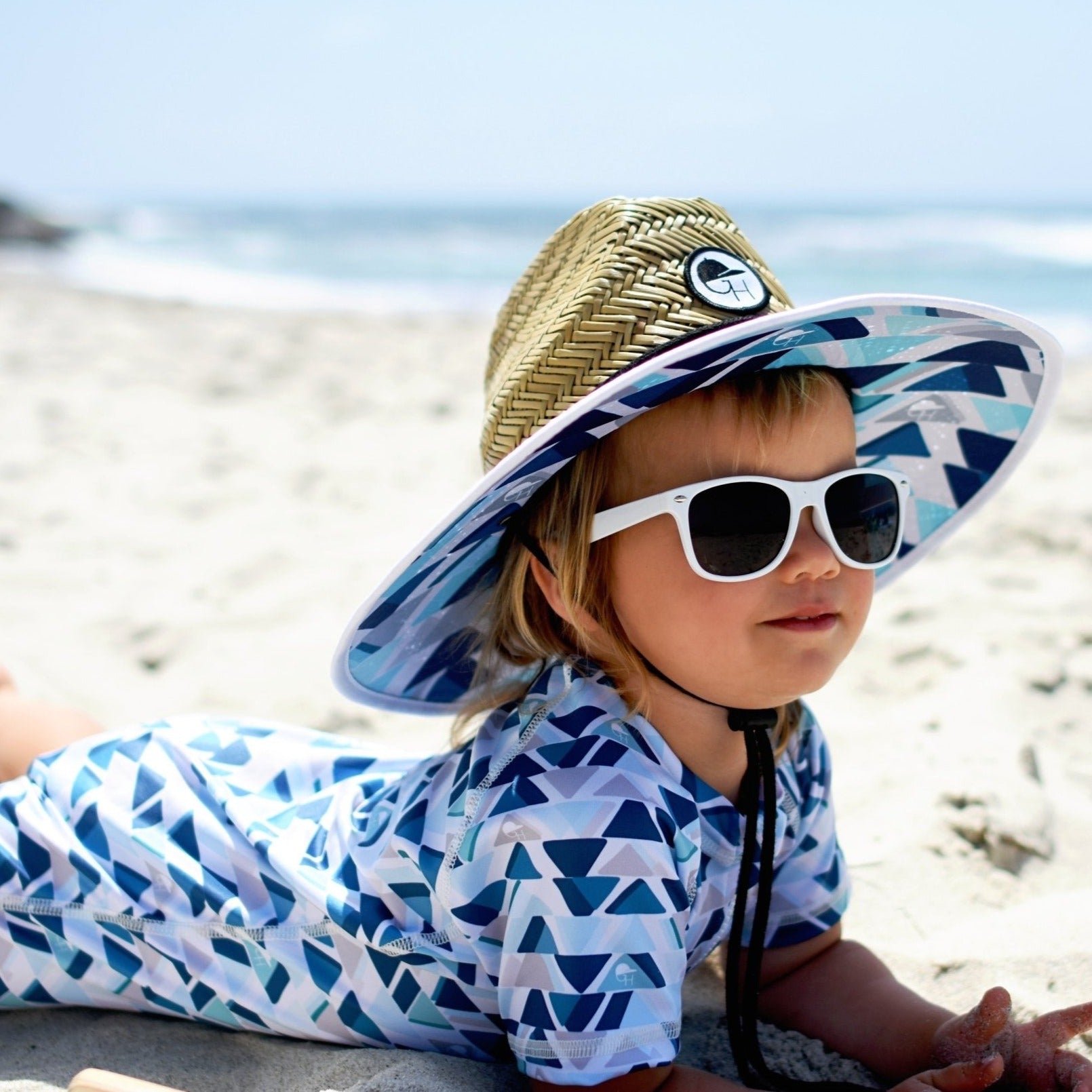 An image of a child in the Waterblue Straw Hat and Sunsuit.